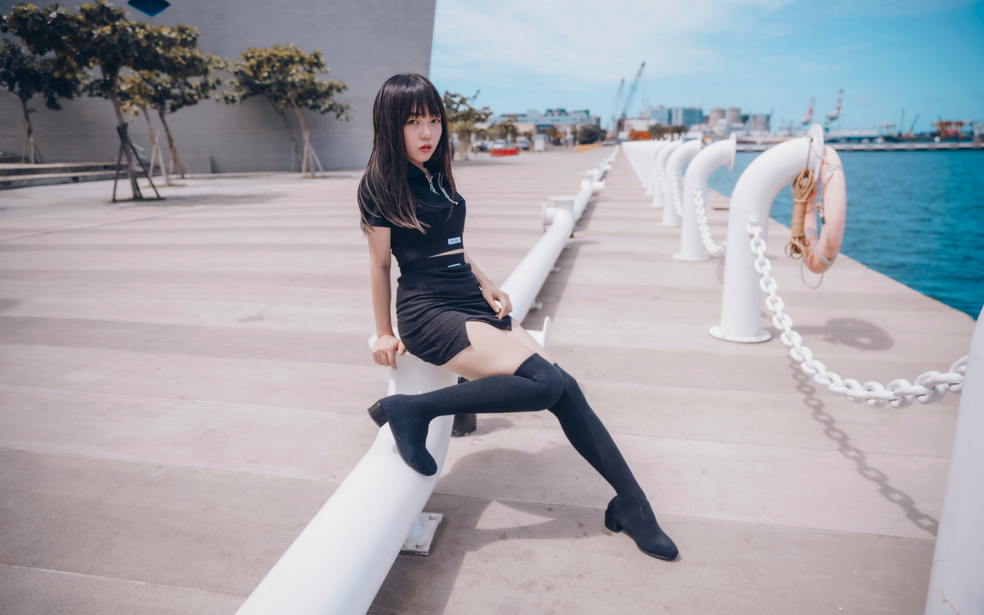 Девушка азиатка в черном костюме на пристани 
