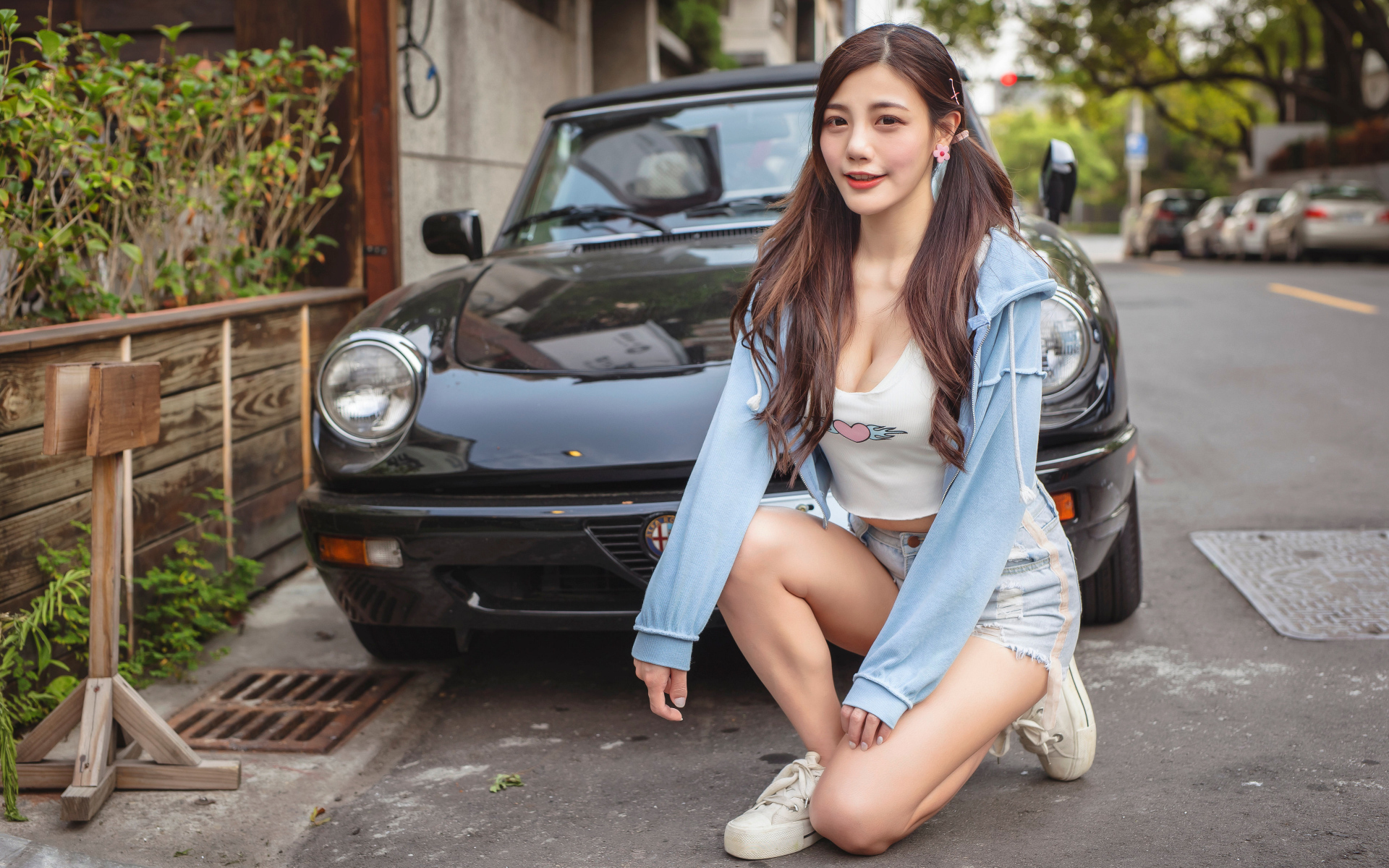 Девушка азиатка сидит возле машины 