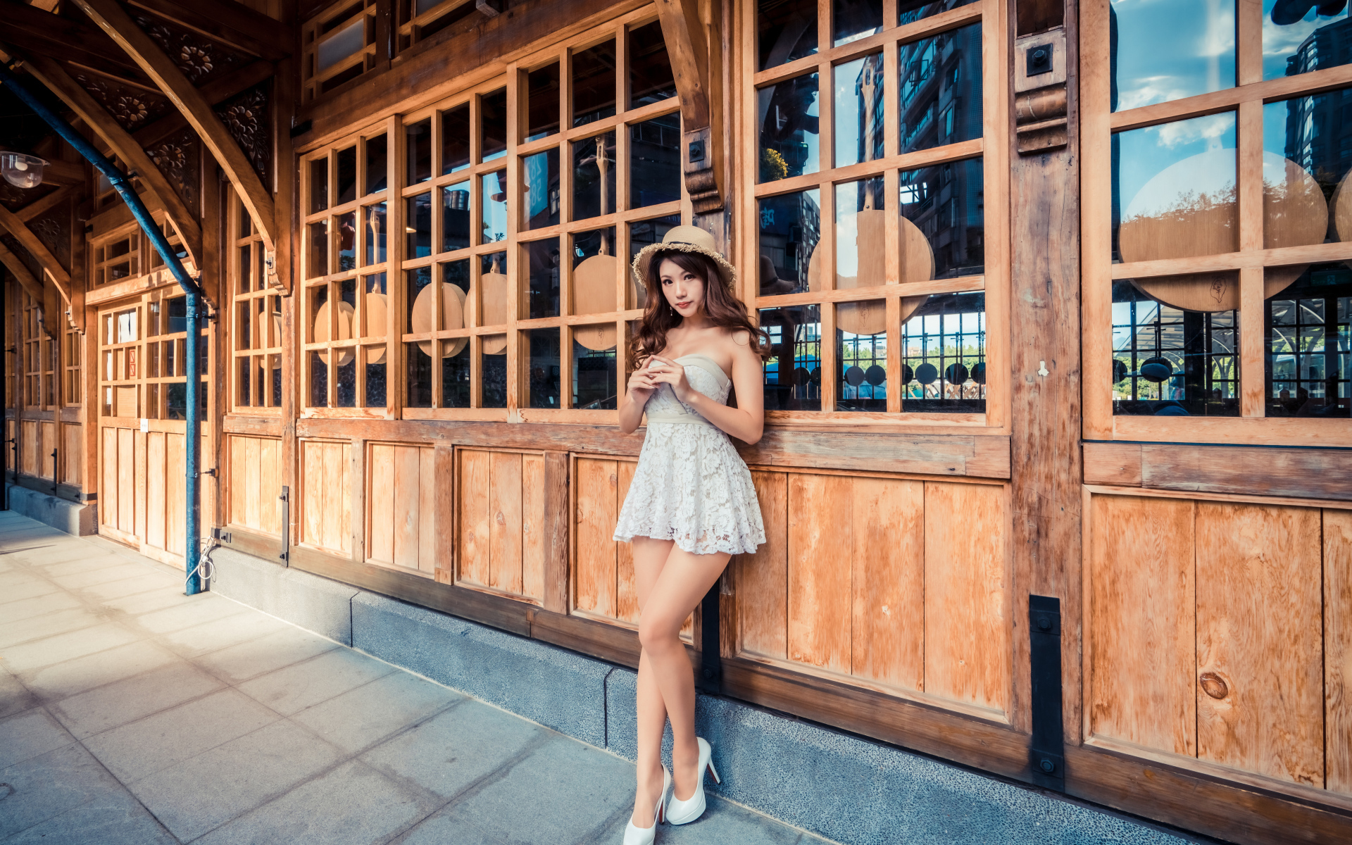 Красивая девушка азиатка стоит у стены с большими окнами