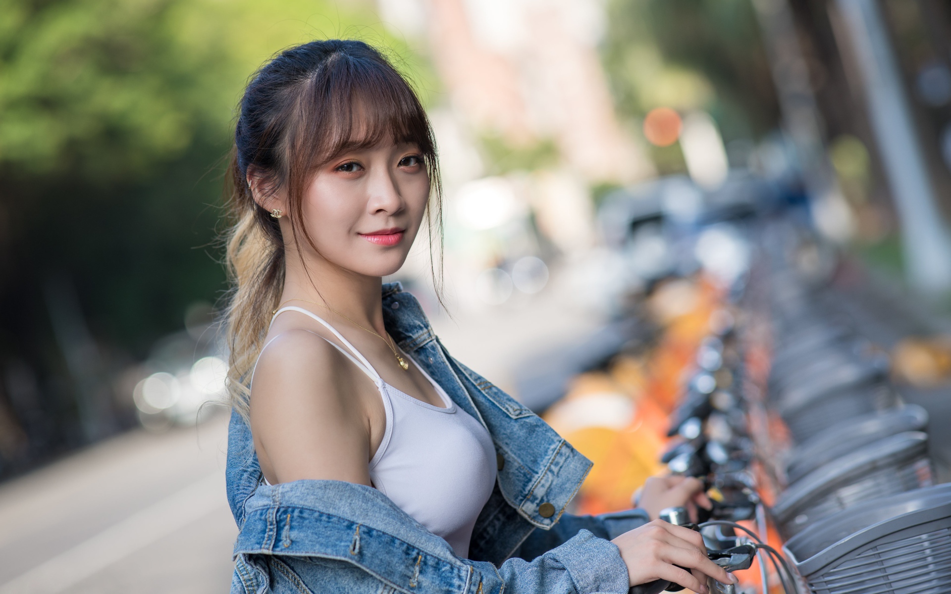 Красивая азиатка в джинсовой куртке с велосипедом