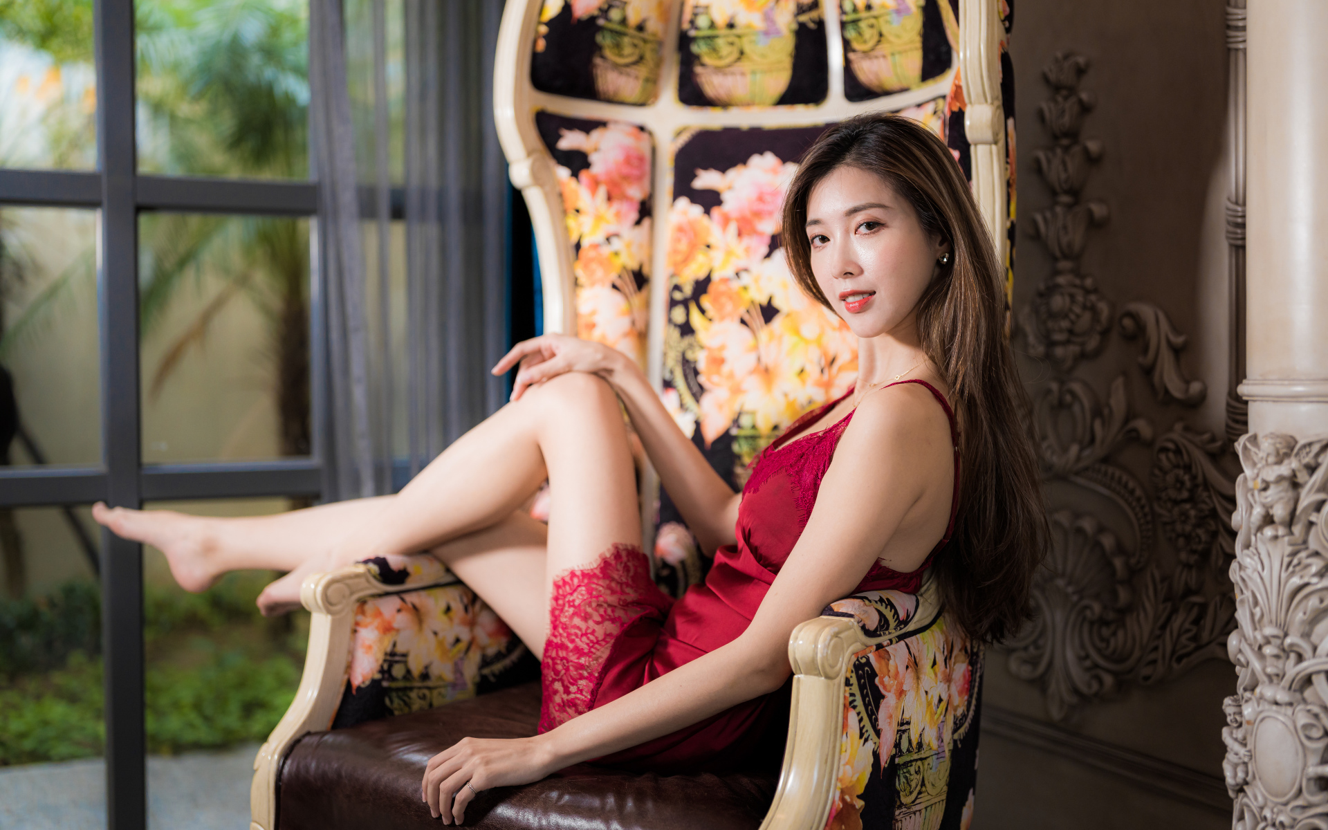 Красивая азиатка в красном платье лежит в кресле
