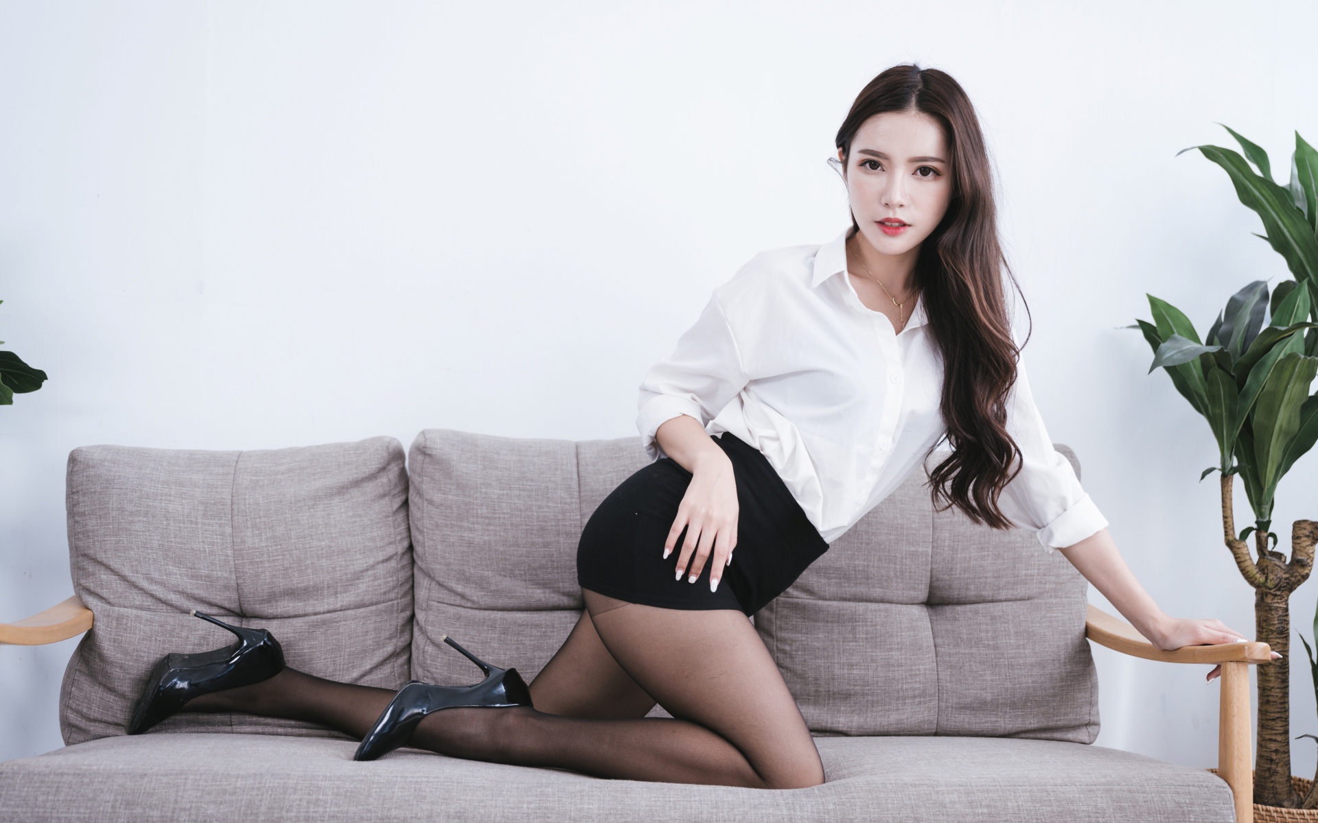 Красивая азиатка в белой рубашке на диване