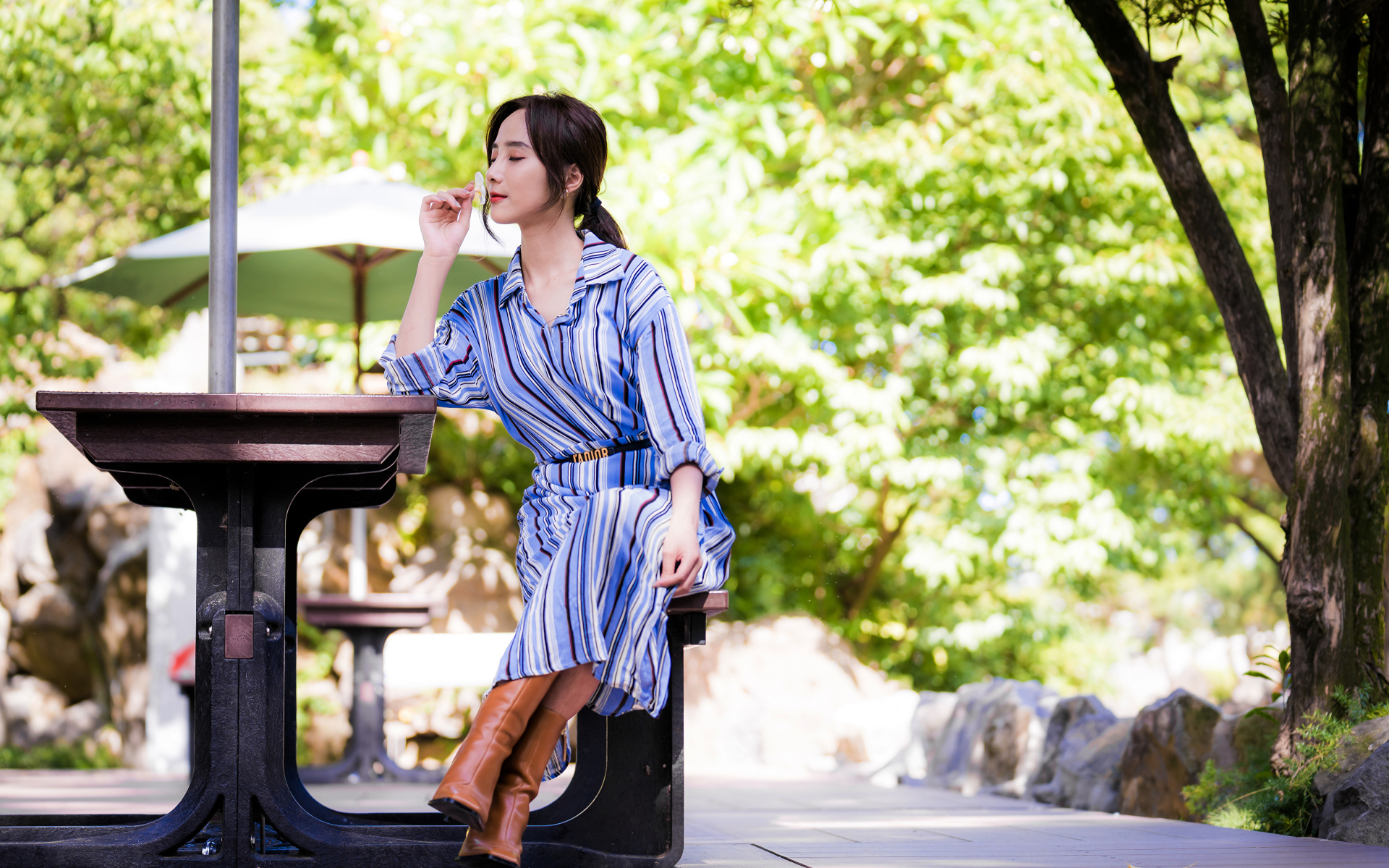 Красивая девушка в платье сидит за столиком в парке