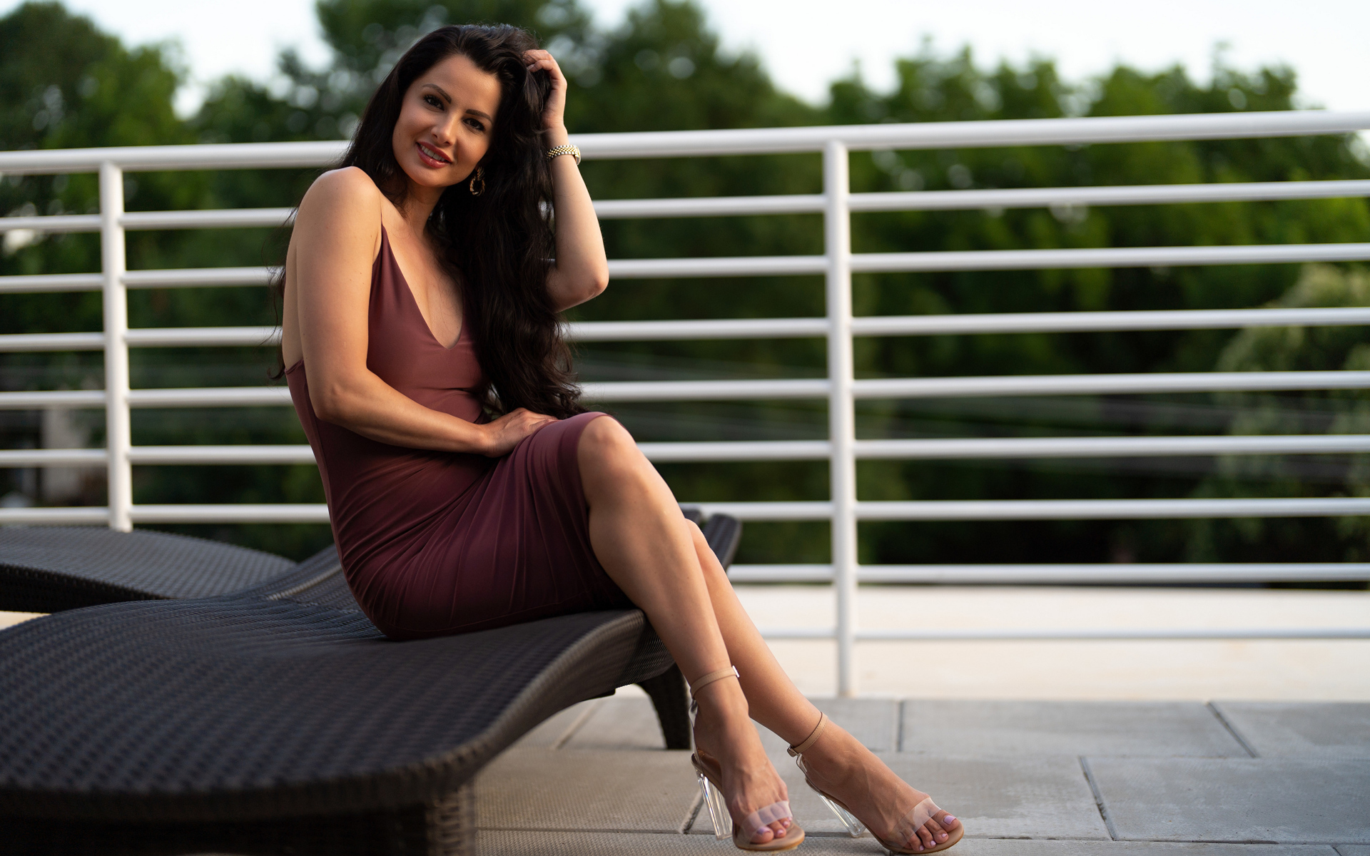 Красивая стильная брюнетка в платье сидит на диване