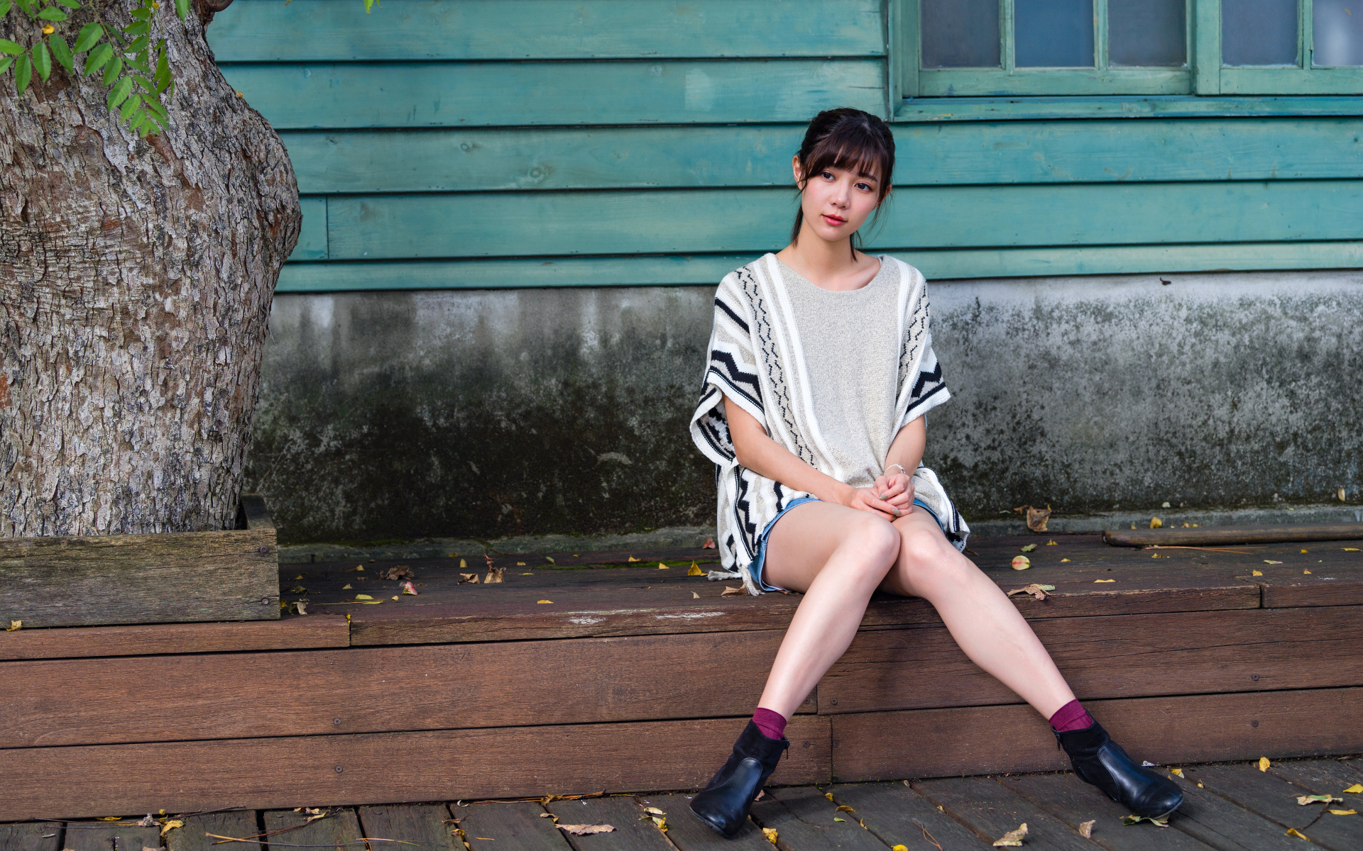 Красивая молодая девушка азиатка сидит у дома