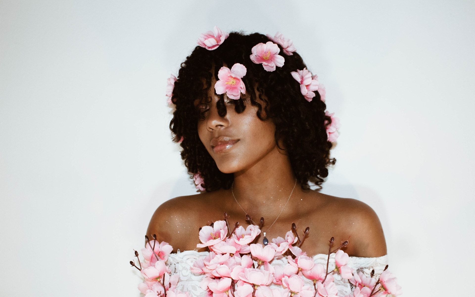 Темнокожая девушка в розовых цветах на сером фоне