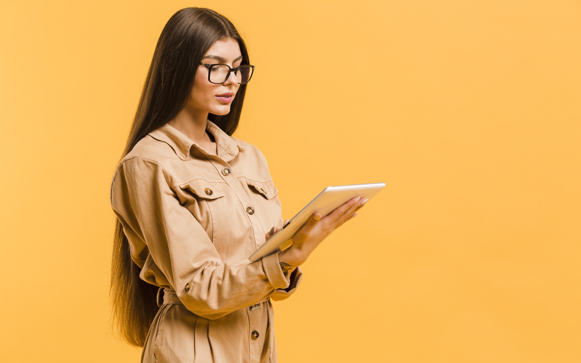 Девушка с планшетов руках на желтом фоне