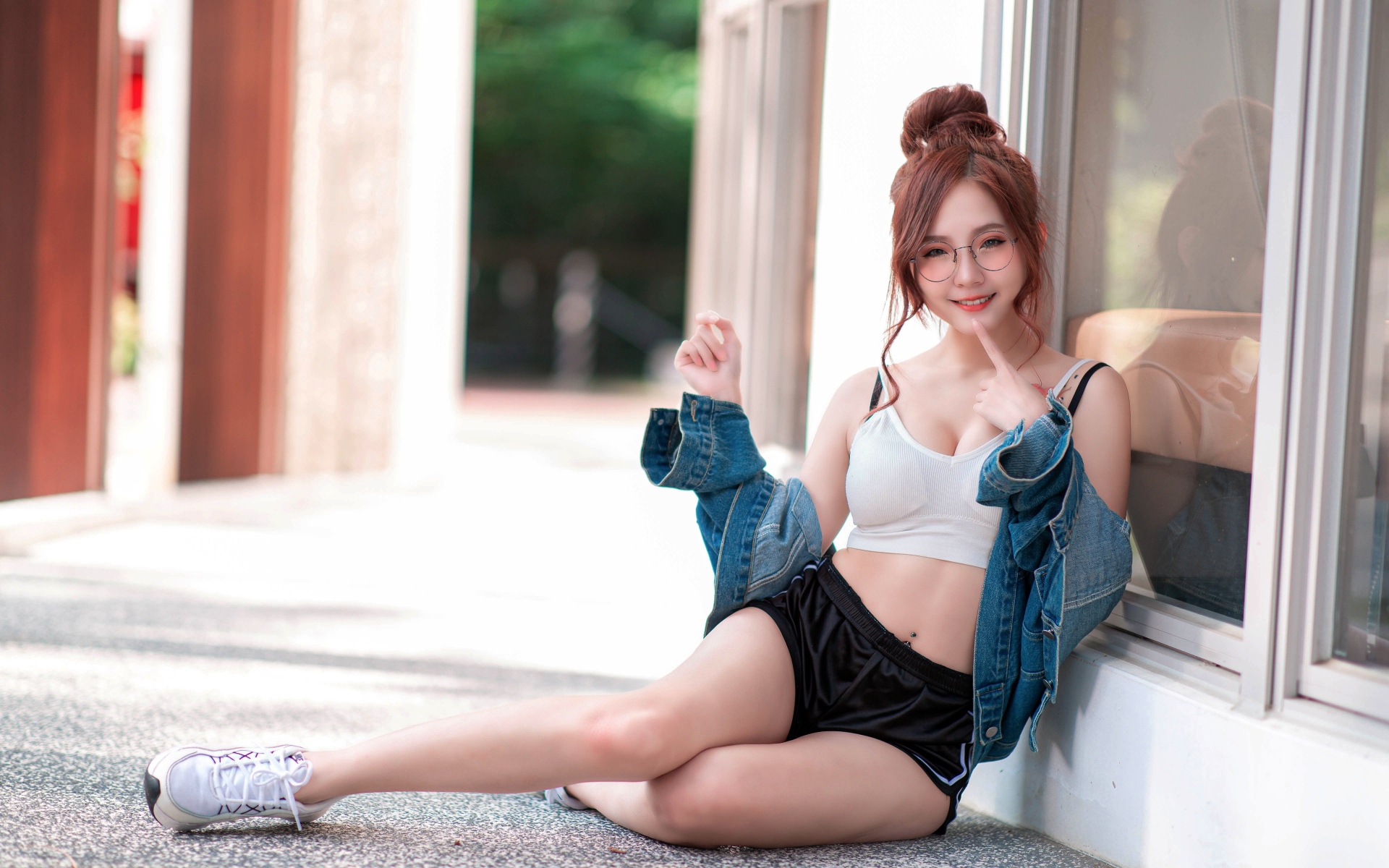 Молодая девушка азиатка в джинсовой куртке сидит у окна