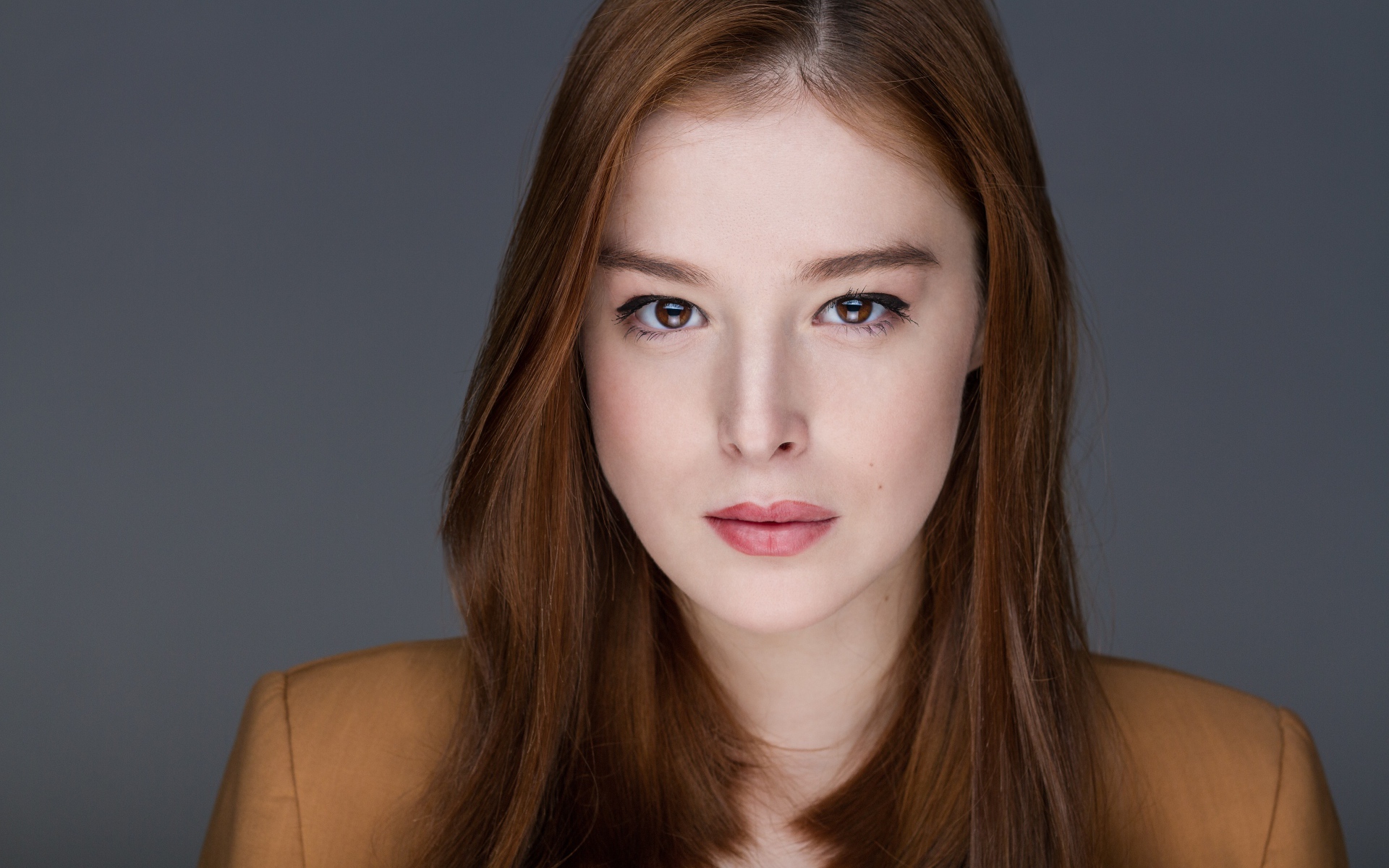 Рыжеволосая  молодая девушка на сером фоне