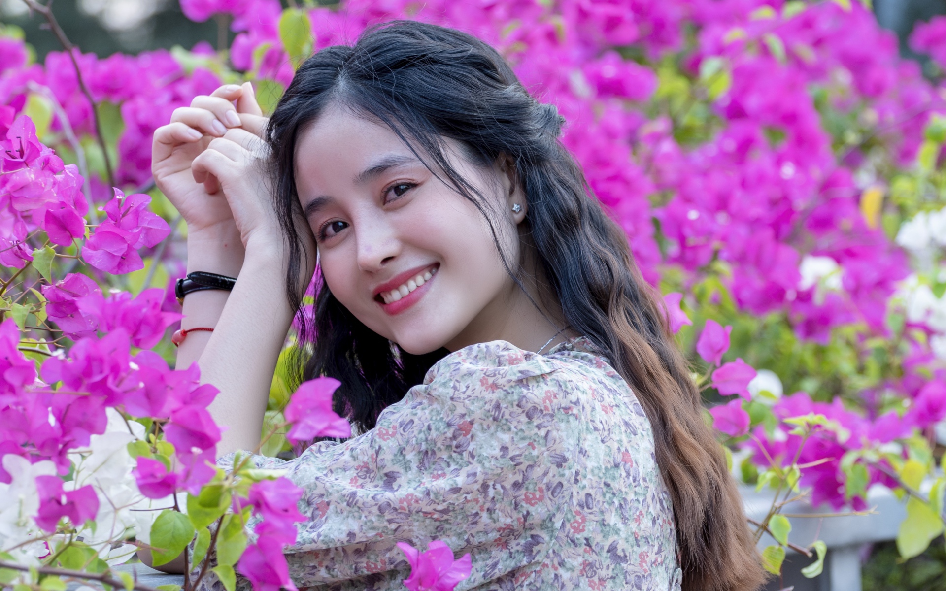 Улыбающаяся девушка азиатка на фоне розовых цветов