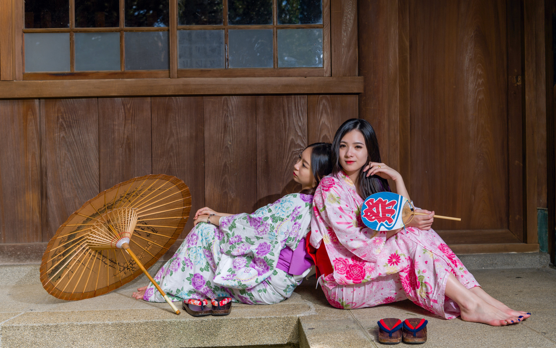 Две молодые девушки в кимоно сидят на полу