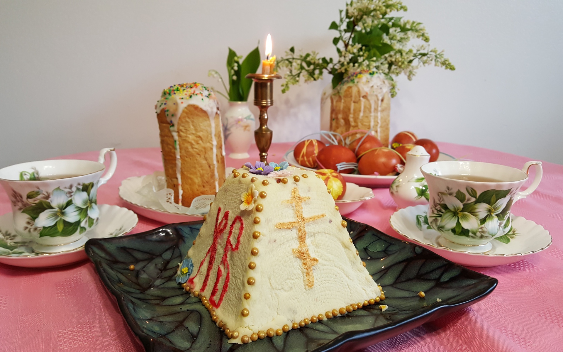 Творожная паска на столе с крашеными яйцами и чаем