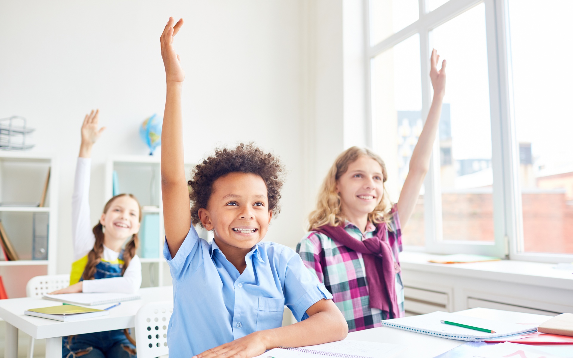 Дети школьники с поднятой  рукой в классе на 1 сентября 