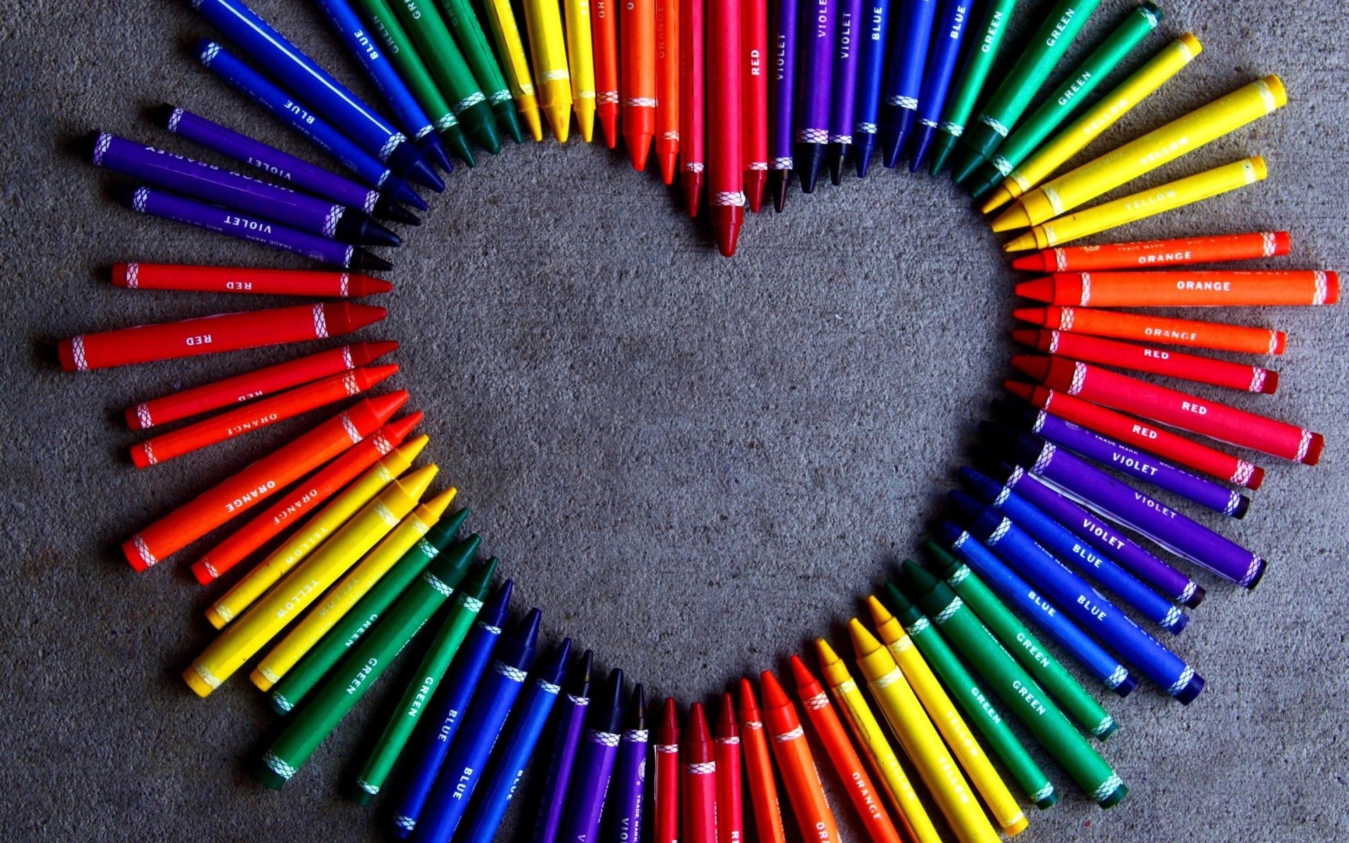 Сердце  из разноцветных карандаш на сером фоне 