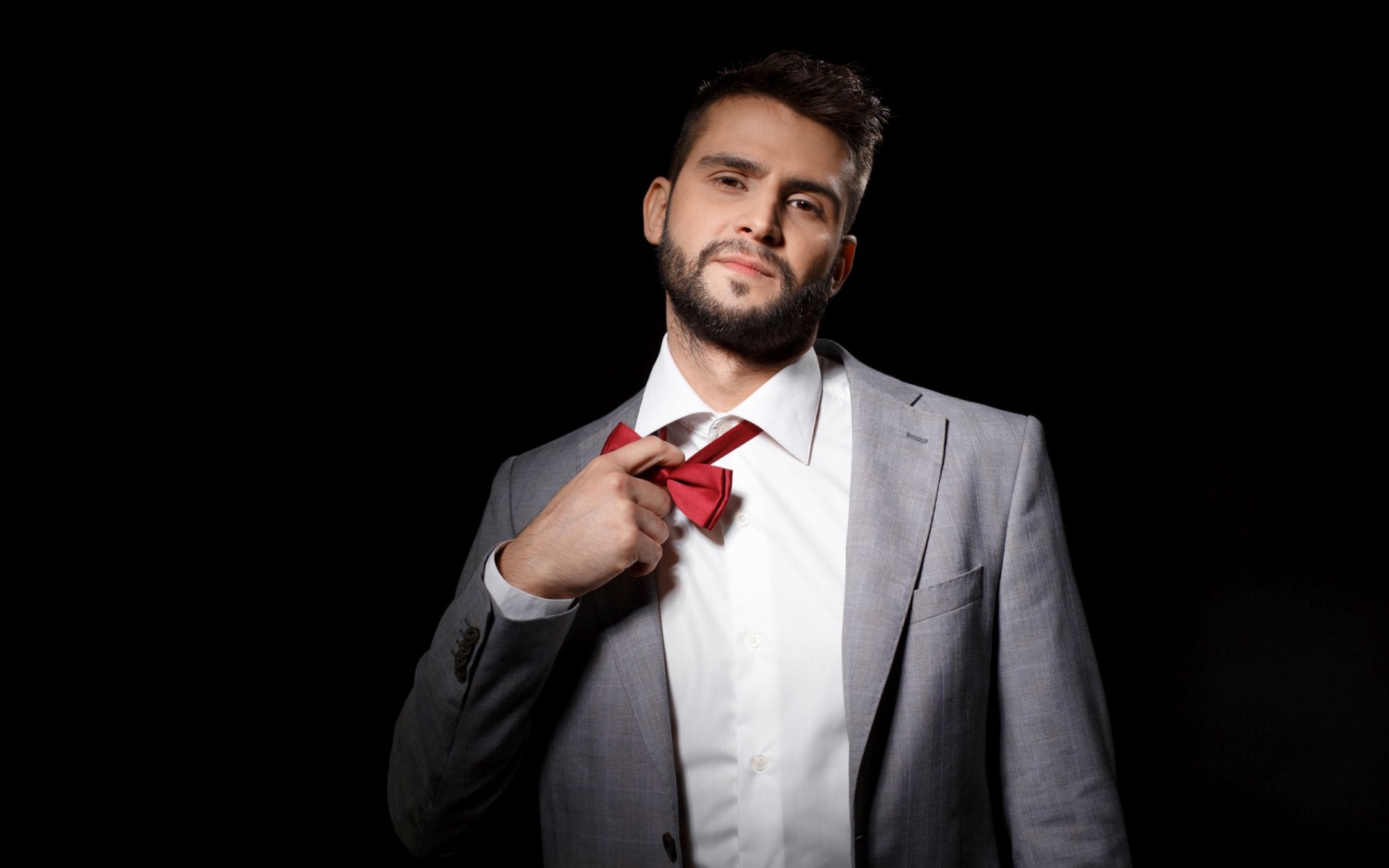 Красивый мужчина в сером пиджаке на черном фоне