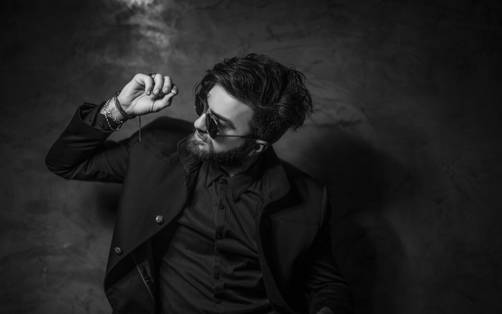 Мужчина в черном костюме на фоне стены