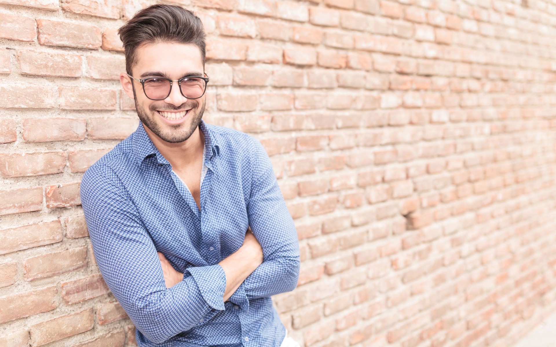 Smiling man with glasses standing against the wall