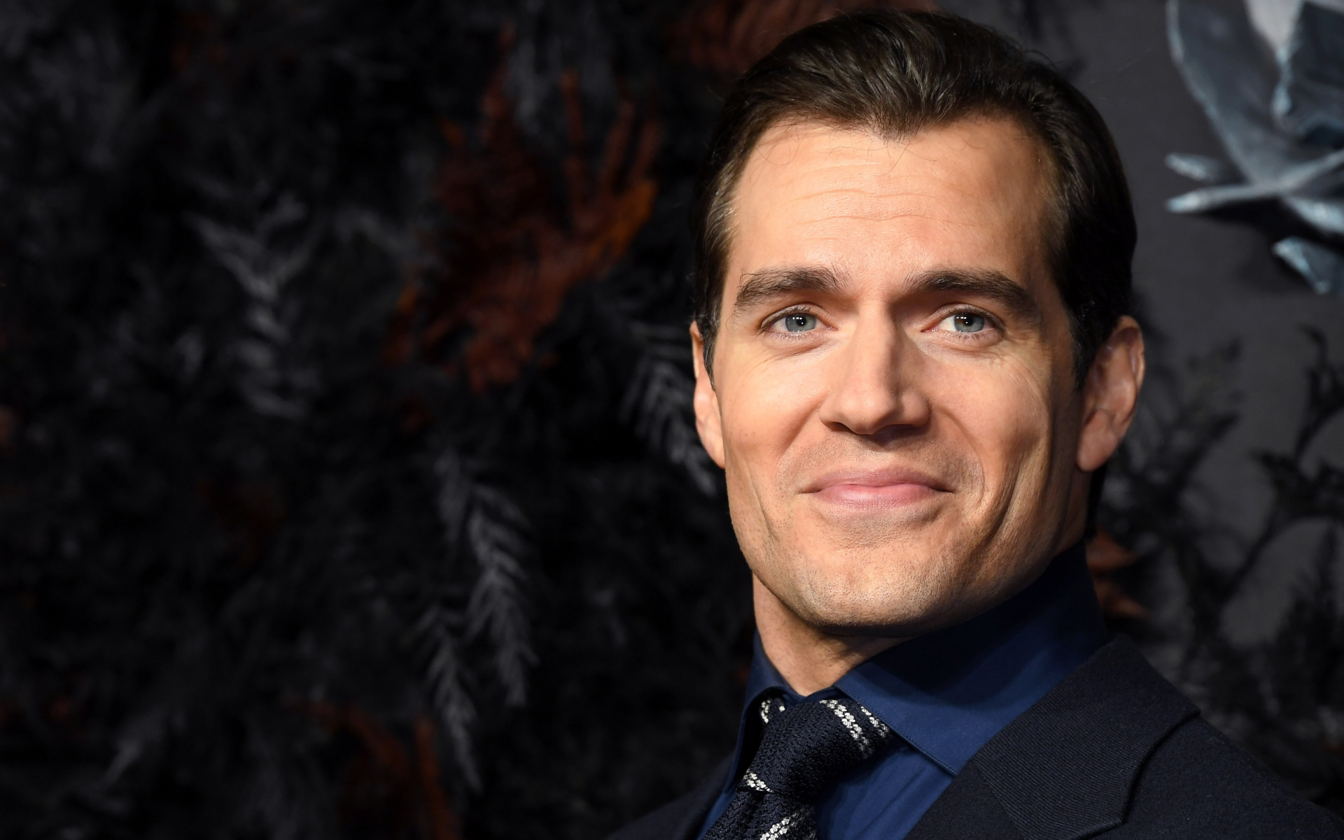 Улыбающийся актер Генри Кавилл в костюме