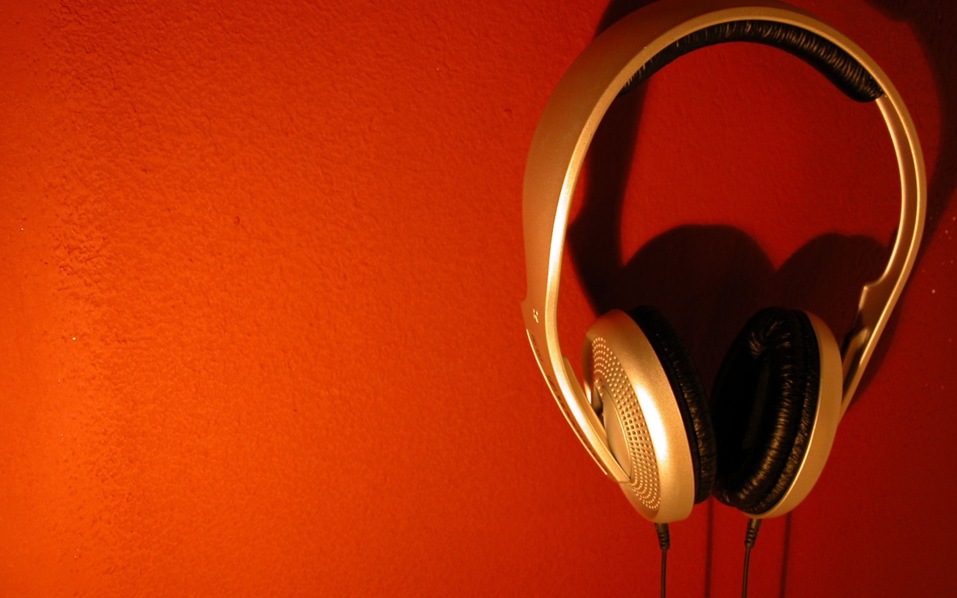 Большие золотые наушники на оранжевом фоне 
