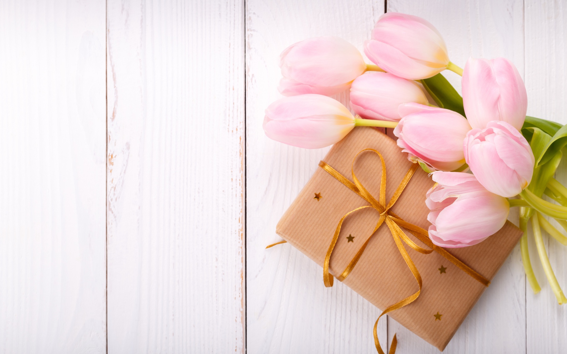 Букет нежных тюльпанов с подарком на деревянном столе