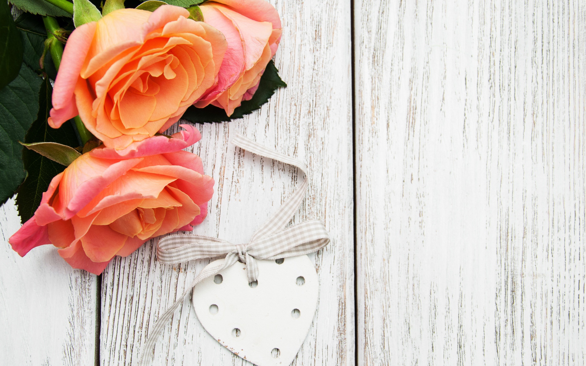 Три оранжевых цветка розы на сером столе