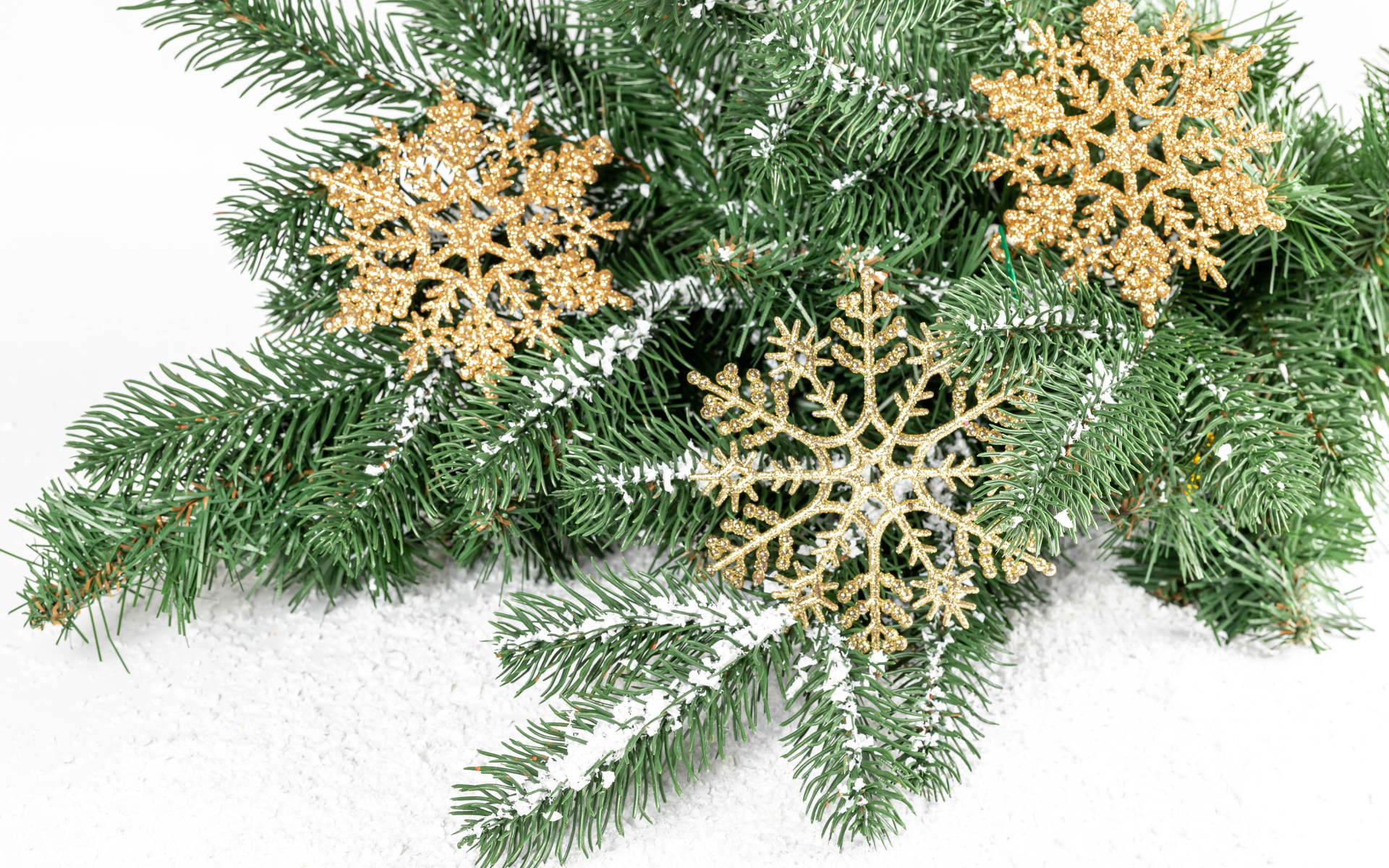 Золотистые снежинки и еловые ветки на снегу