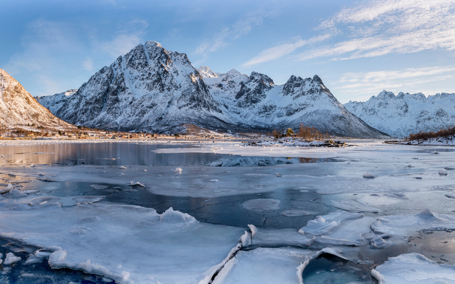 Покрытое льдом озеро у заснеженной горы