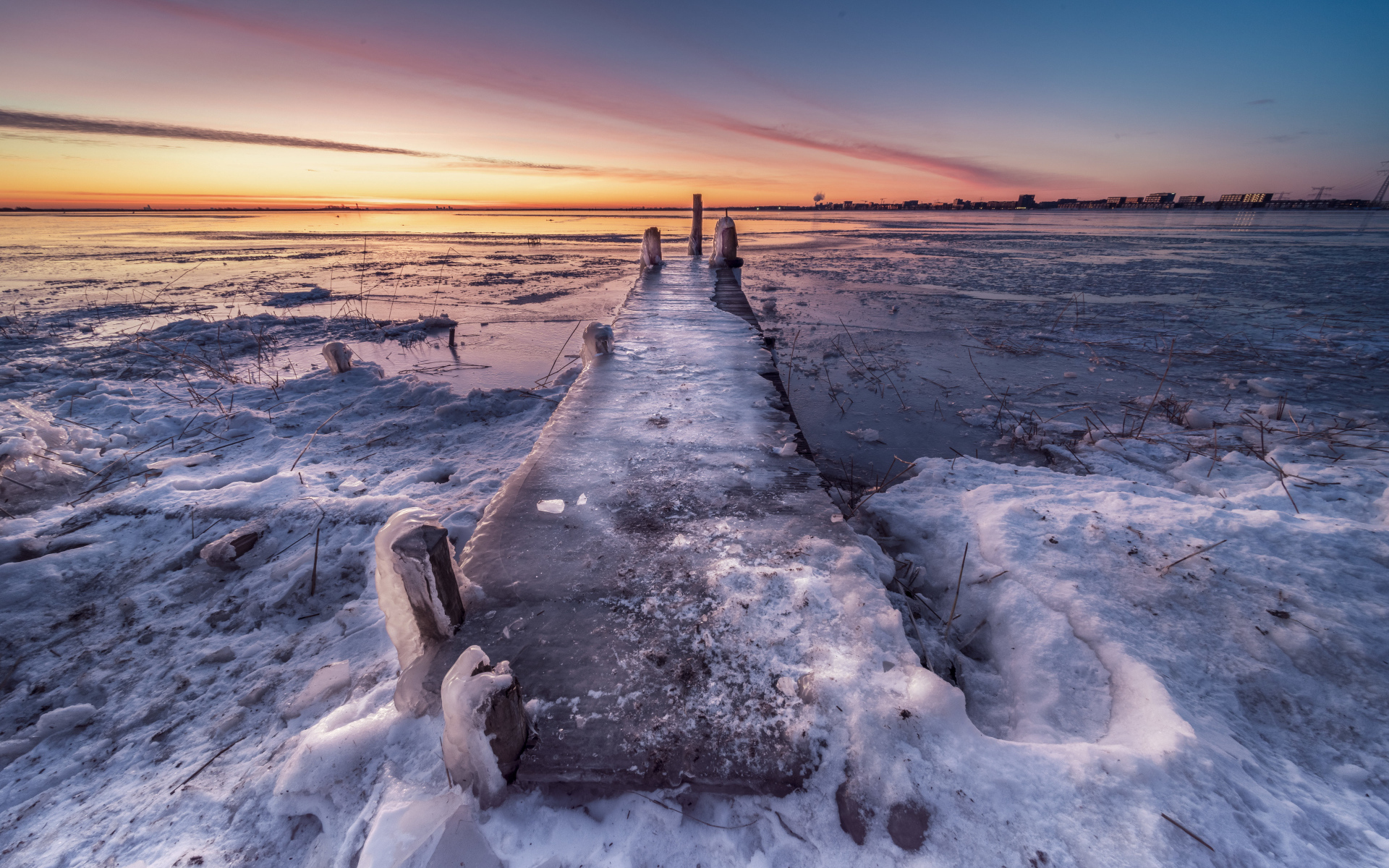 Покрытый льдом деревянный мост у озера 
