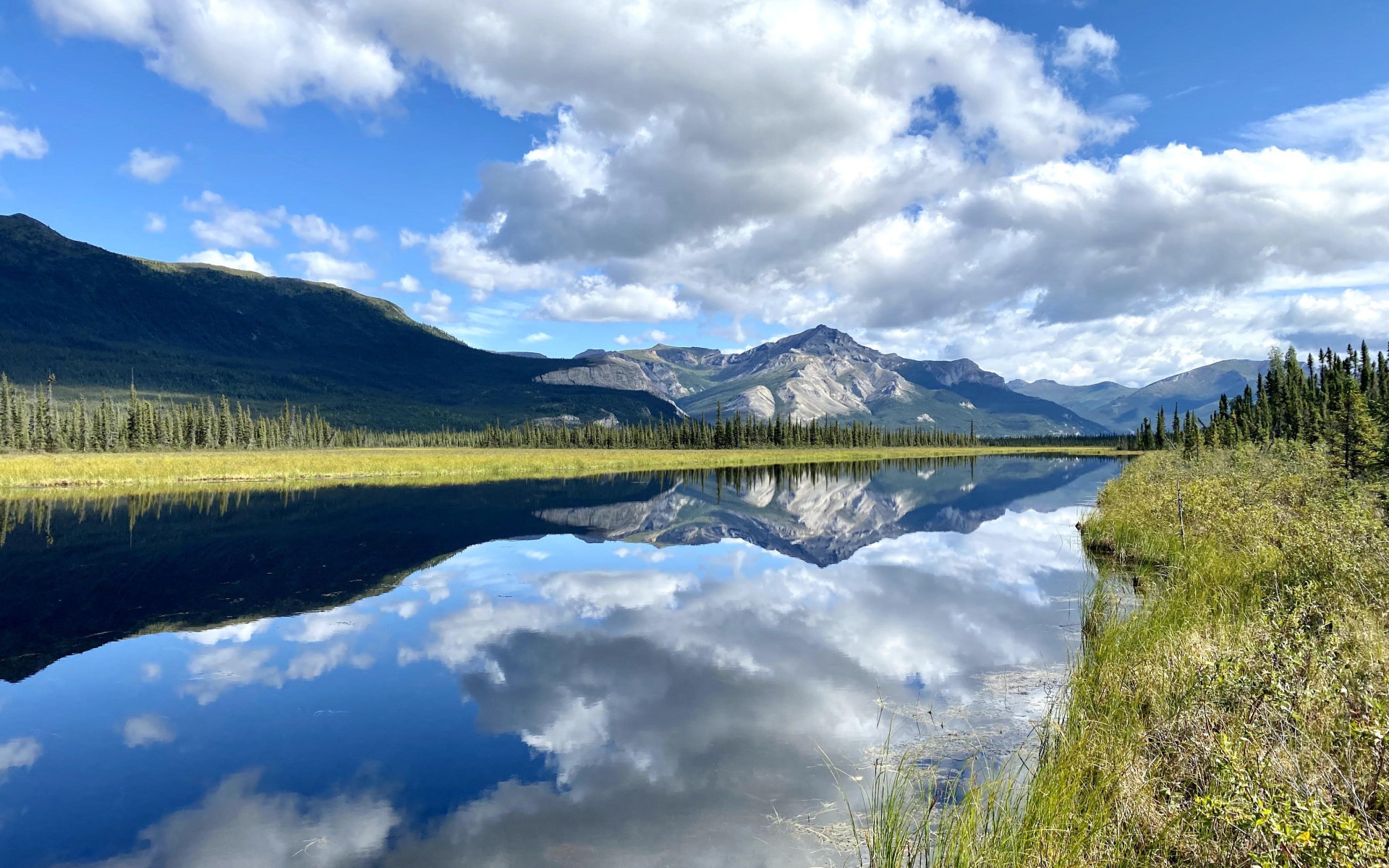 Небо с белыми облаками отражается в реке 