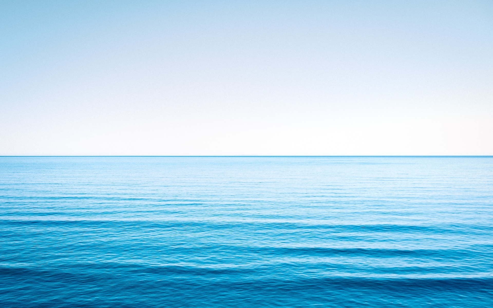 Спокойная голубая морская вода под голубым небом 