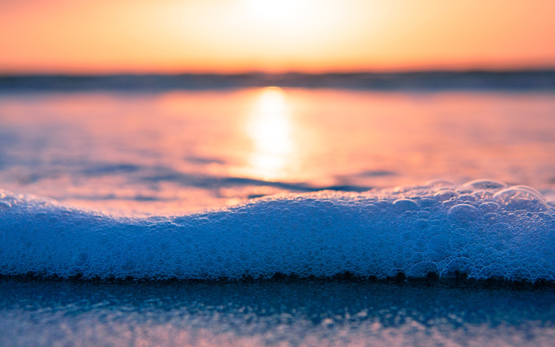 Белая морская пена с пузырям на закате