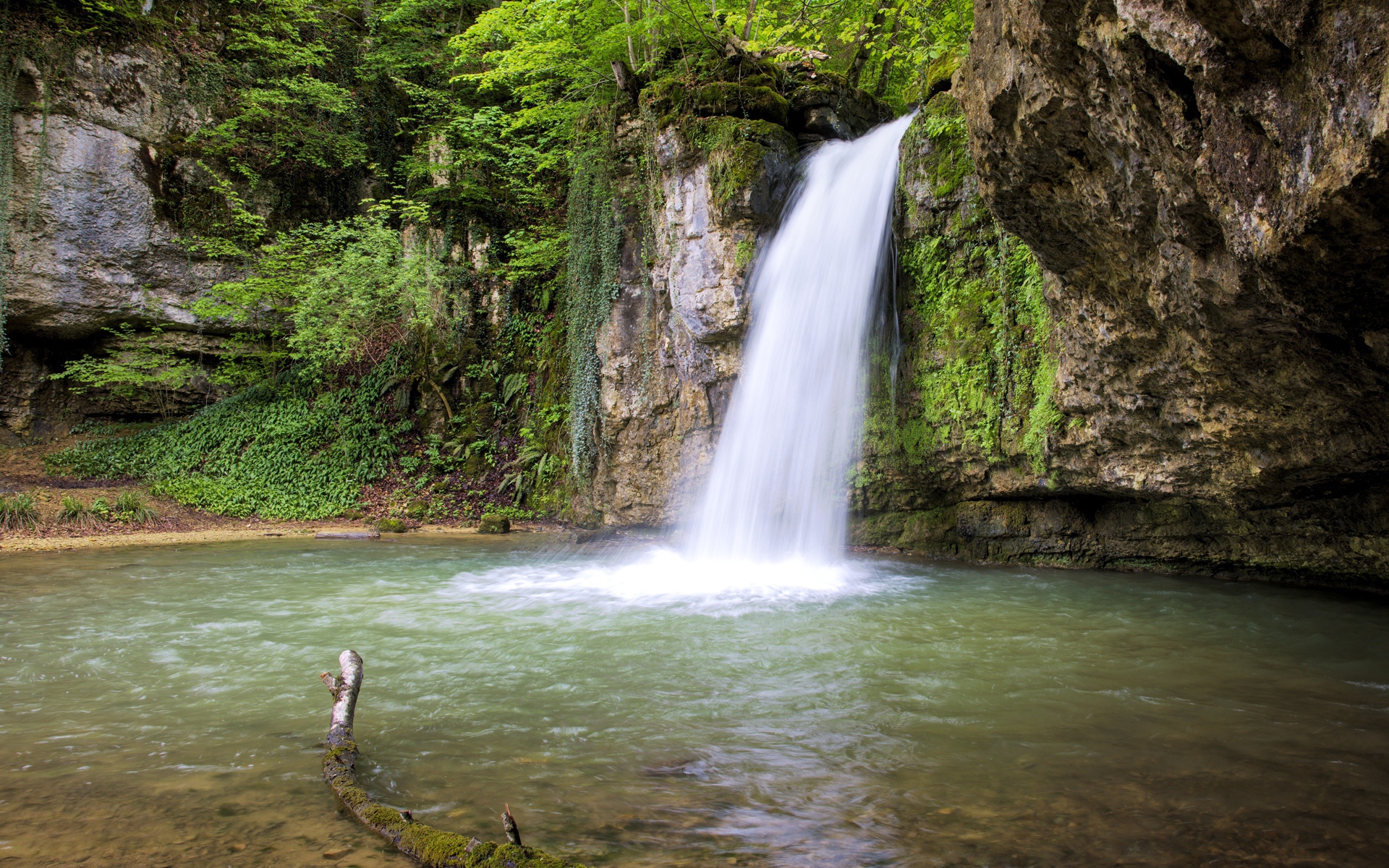 Водопад стекает с крутой горы в озеро 