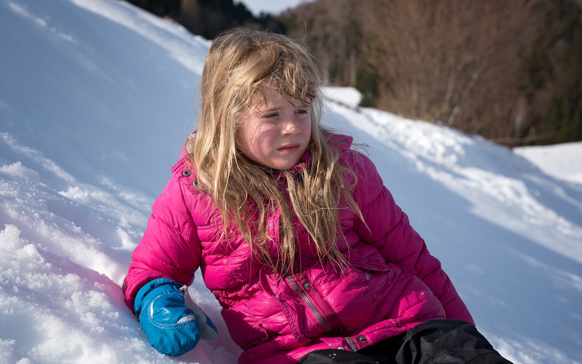 Маленькая девочка лежит на заснеженной горке 