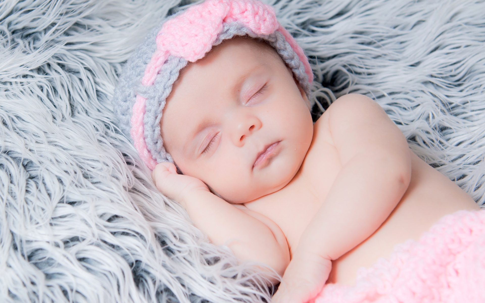 Грудной ребенок спит на меховом одеяле 