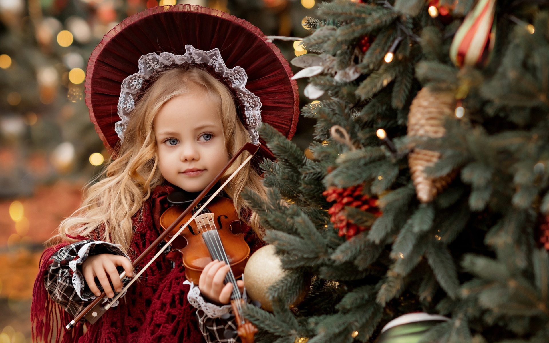 Красивая маленькая девочка со скрипкой у ели