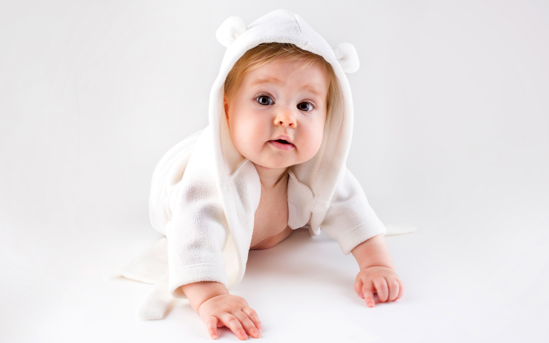 Забавный малыш ползает в белом наряде 