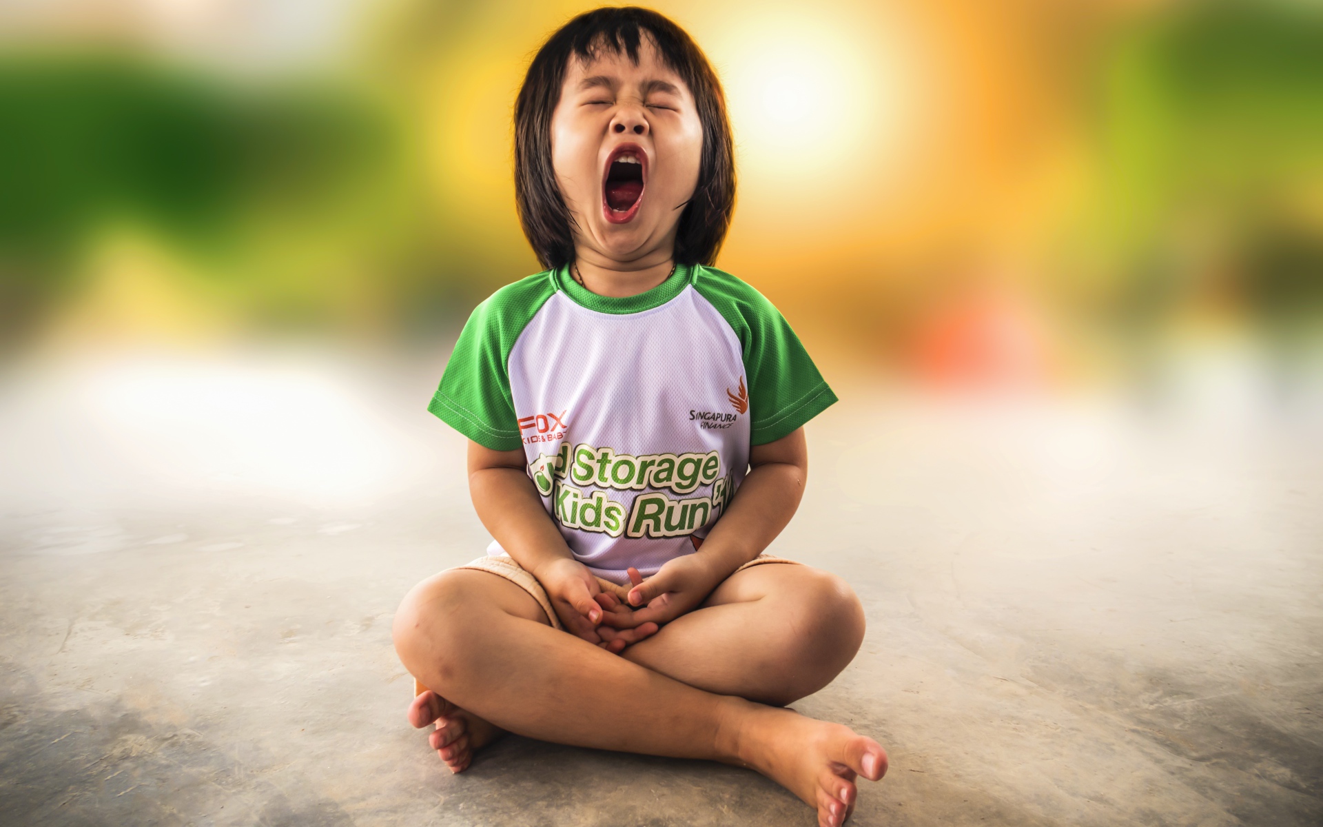 Маленькая девочка азиатка зевает на полу