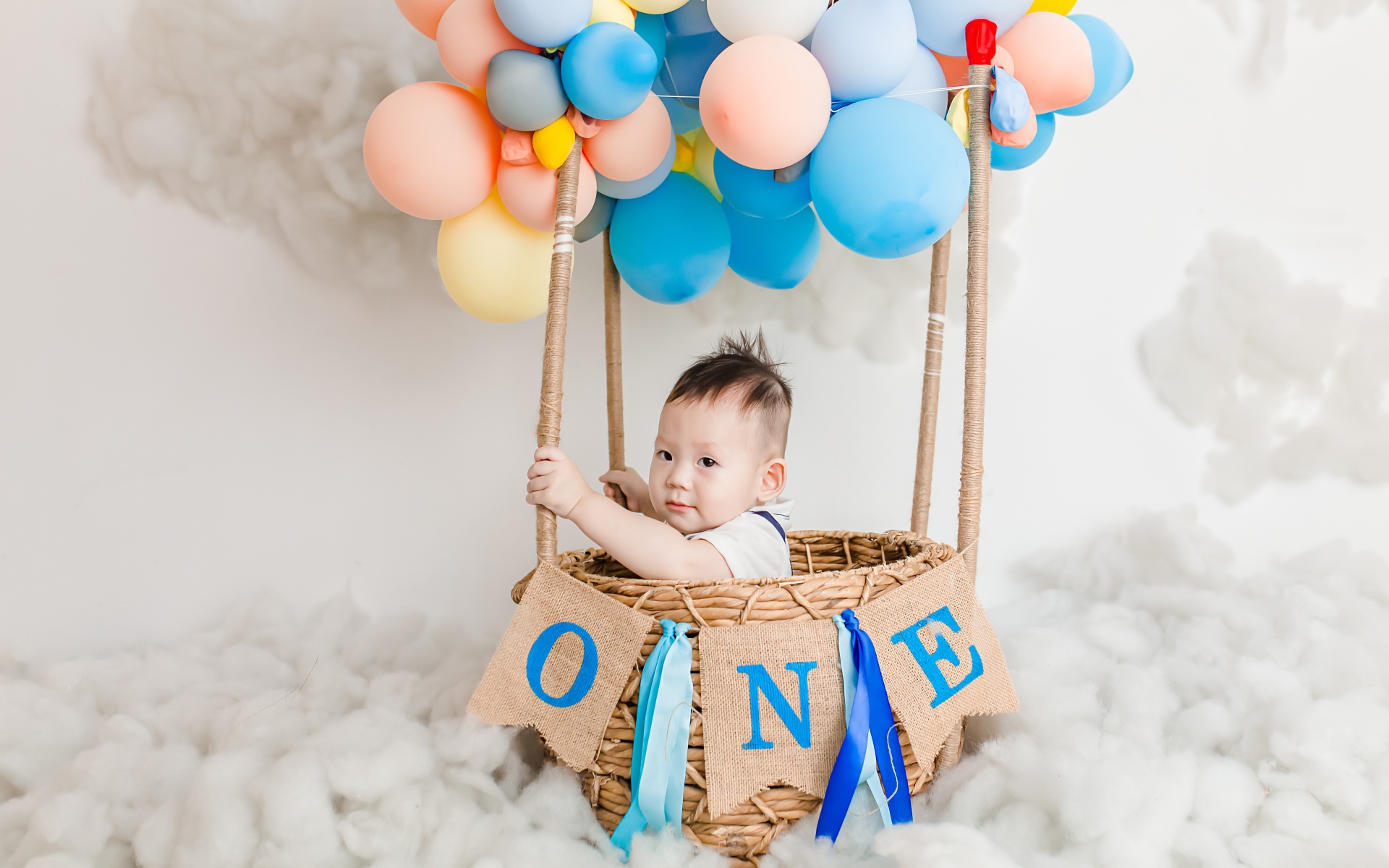 Маленький ребенок в корзине с шариками 