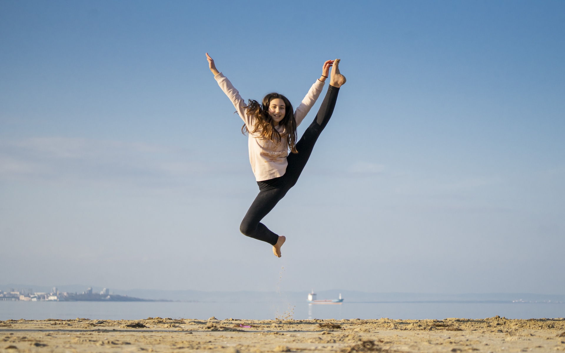 Маленькая девочка гимнастка на песке