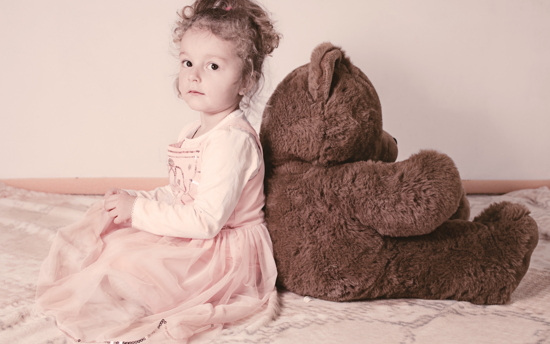 Маленькая девочка сидит с большим медведем