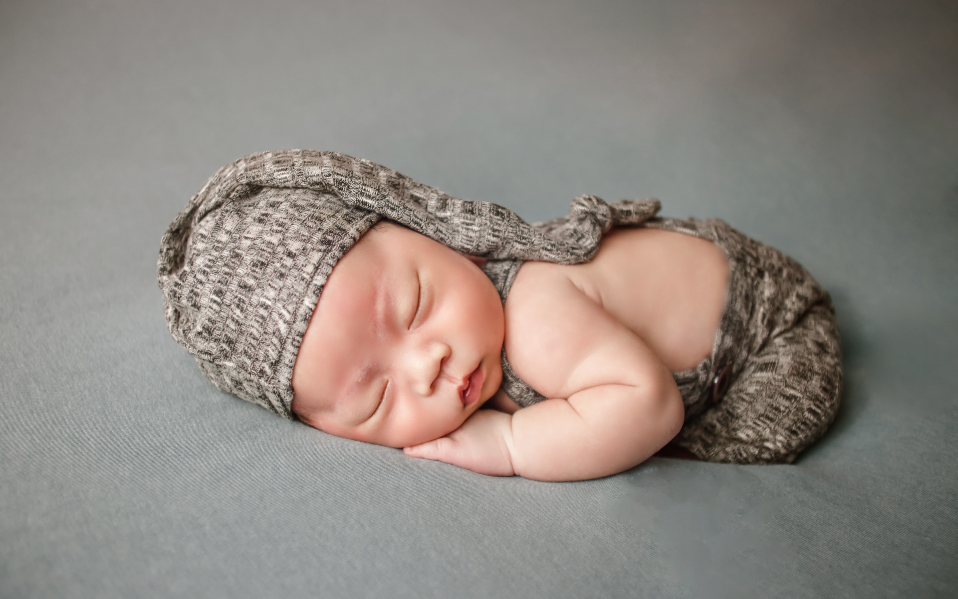 Маленький новорожденный ребенок на сером фоне