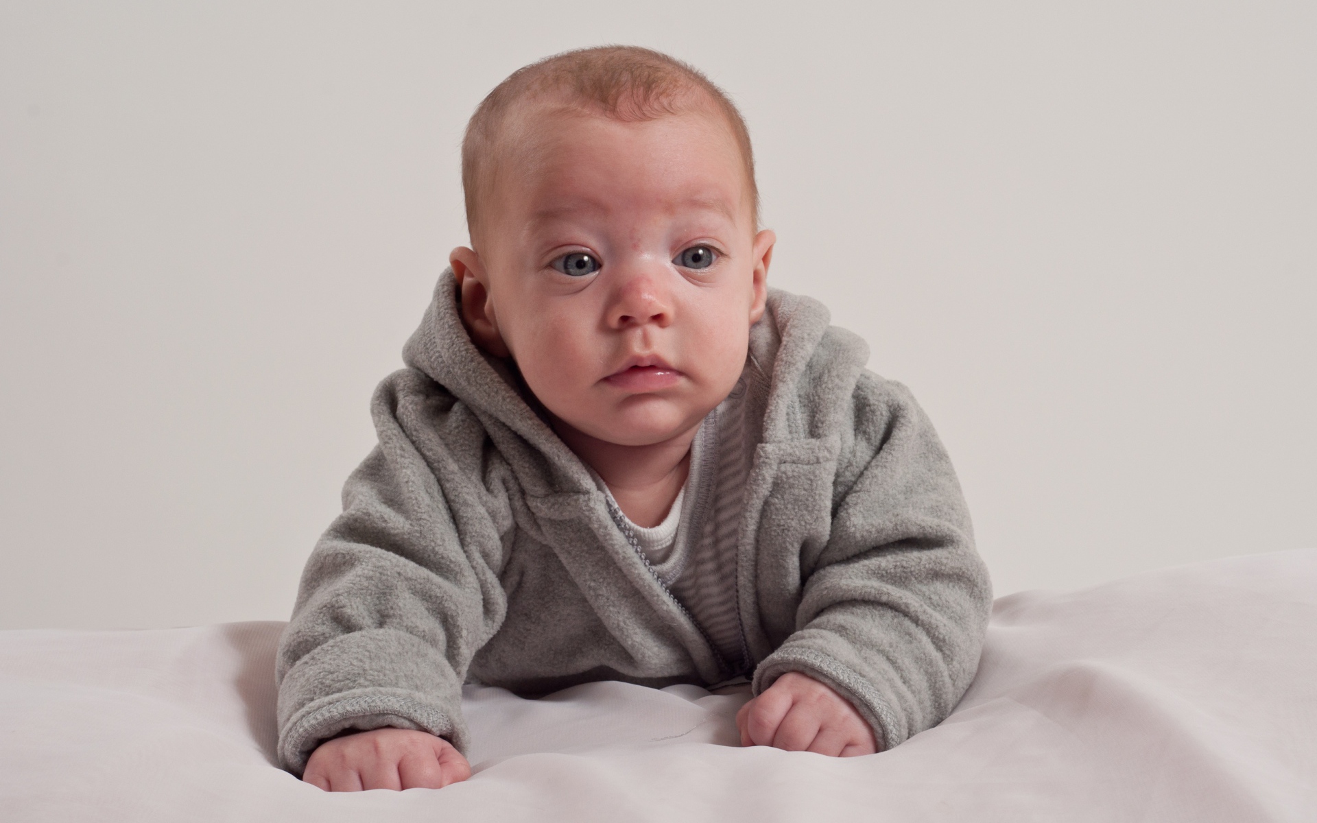 Маленький новорожденный мальчик в сером костюме