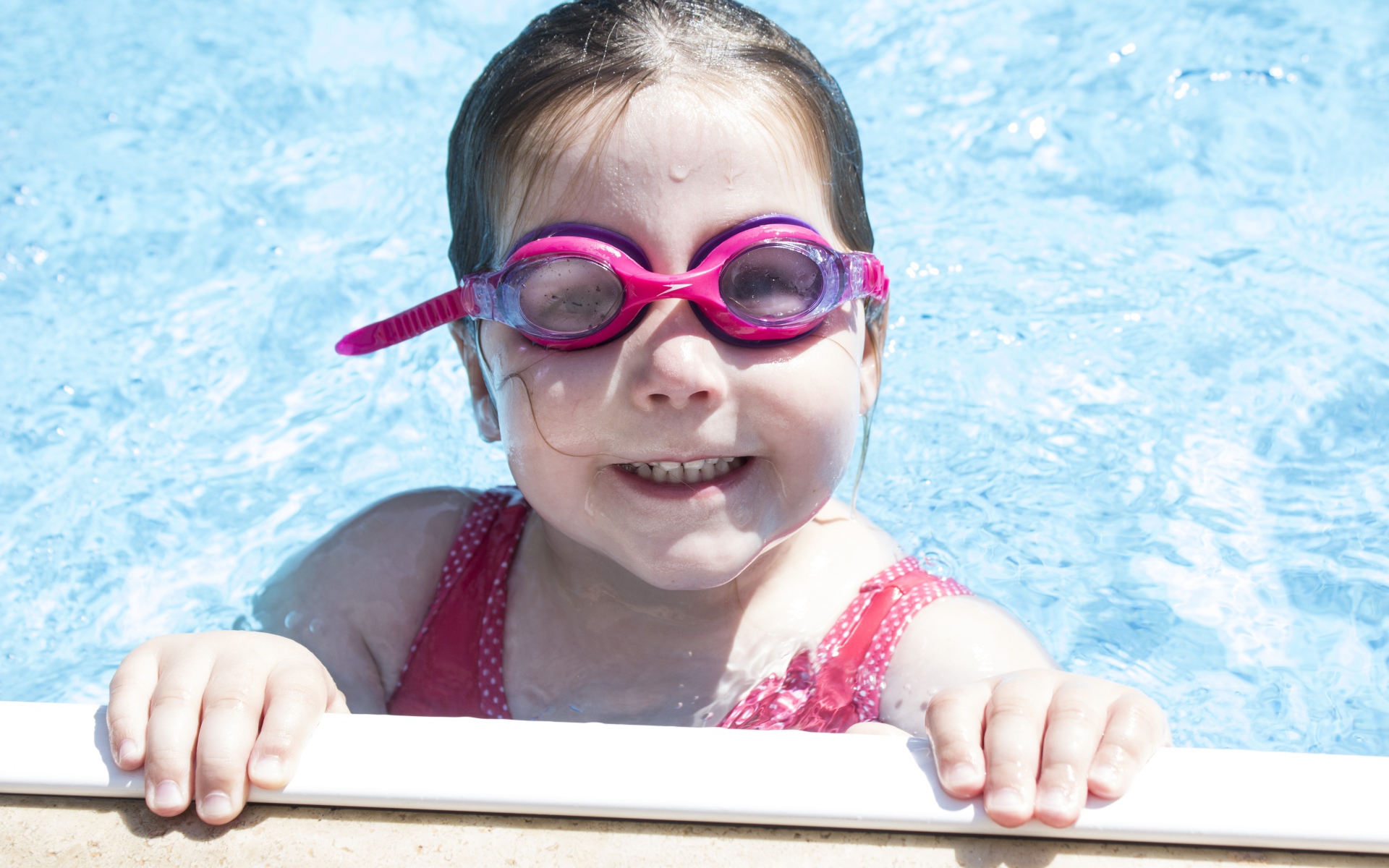 Улыбающаяся девочка в очках в бассейне