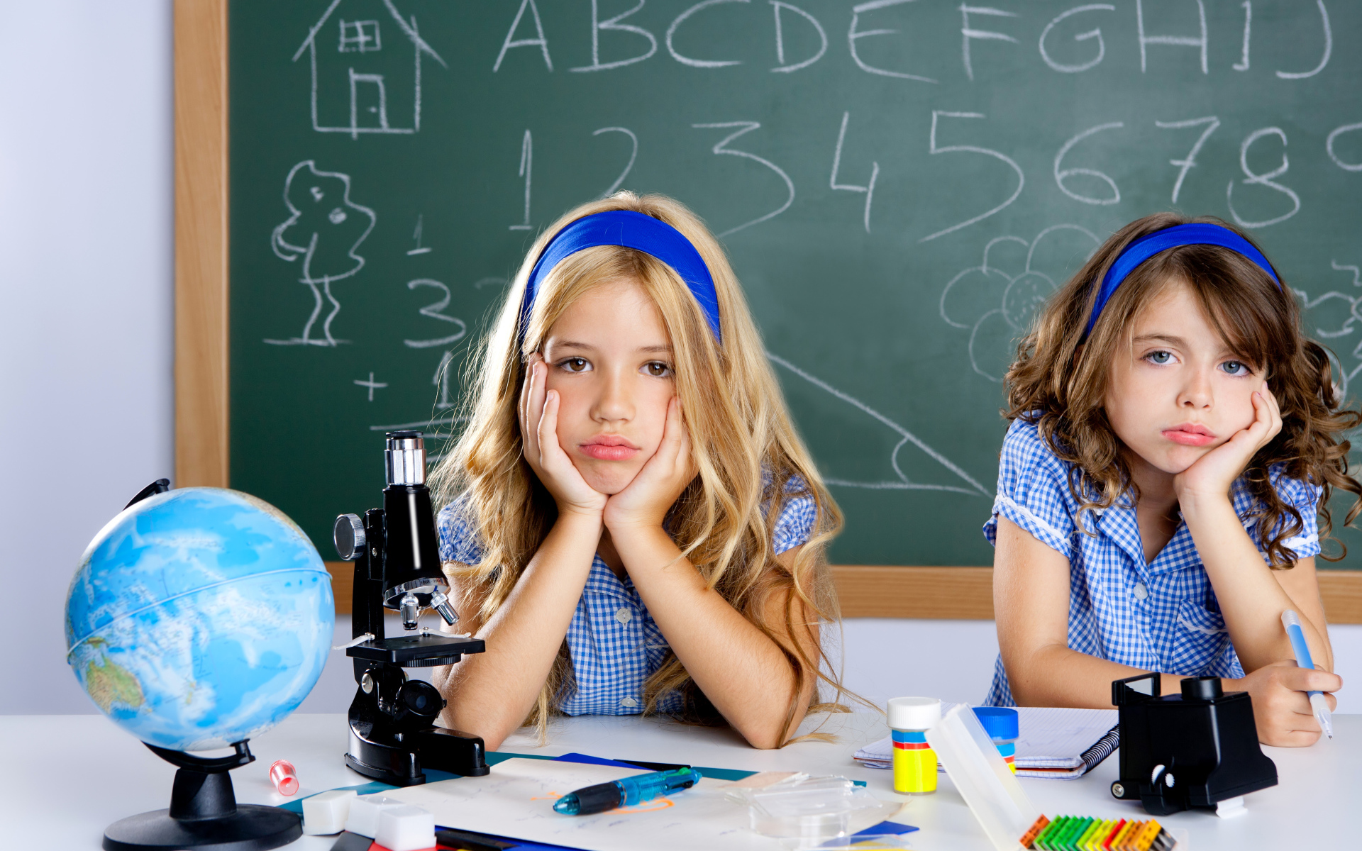 Две грустные девочка за партой в школе
