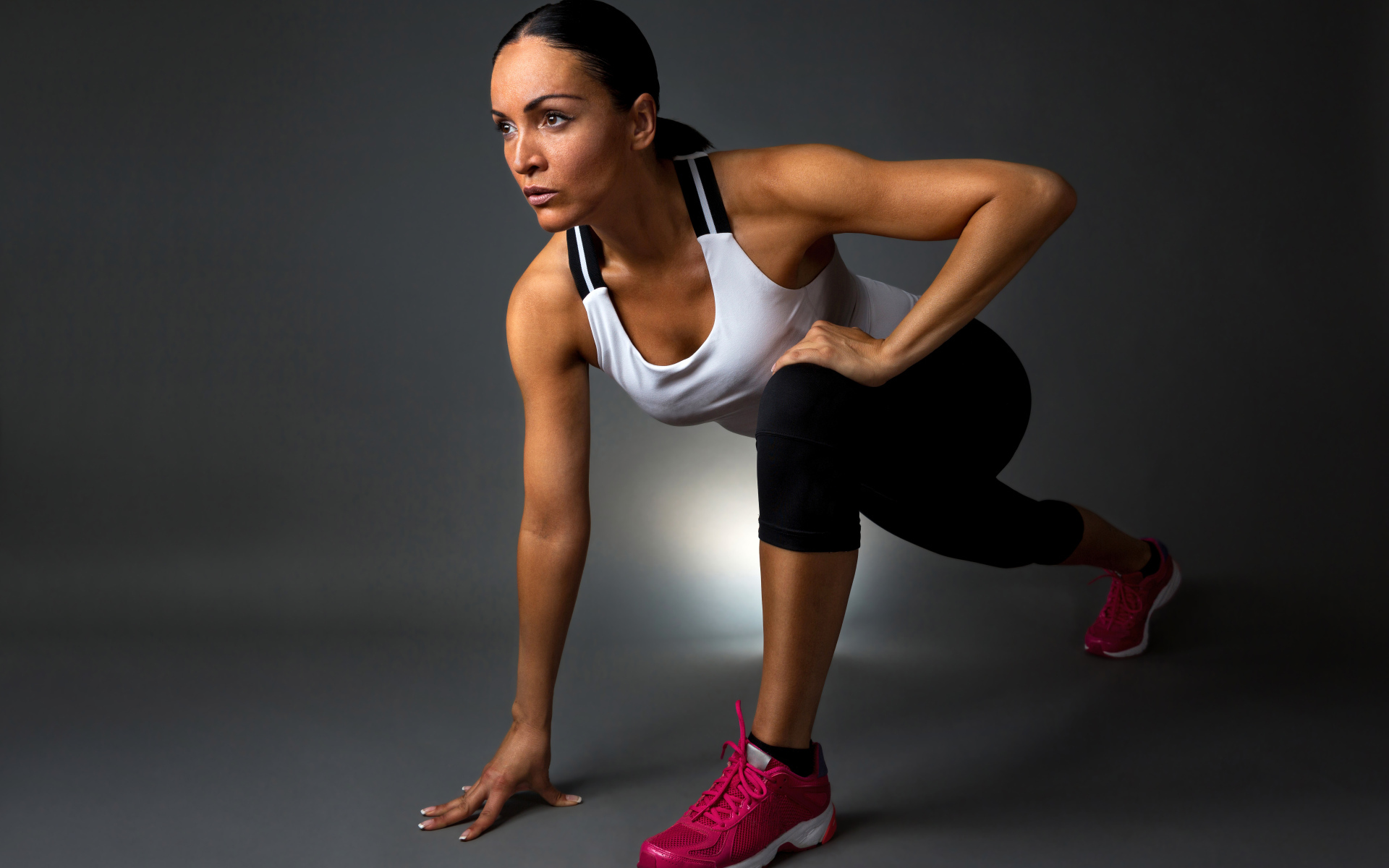 Девушка спортсменка в стойке на сером фоне 