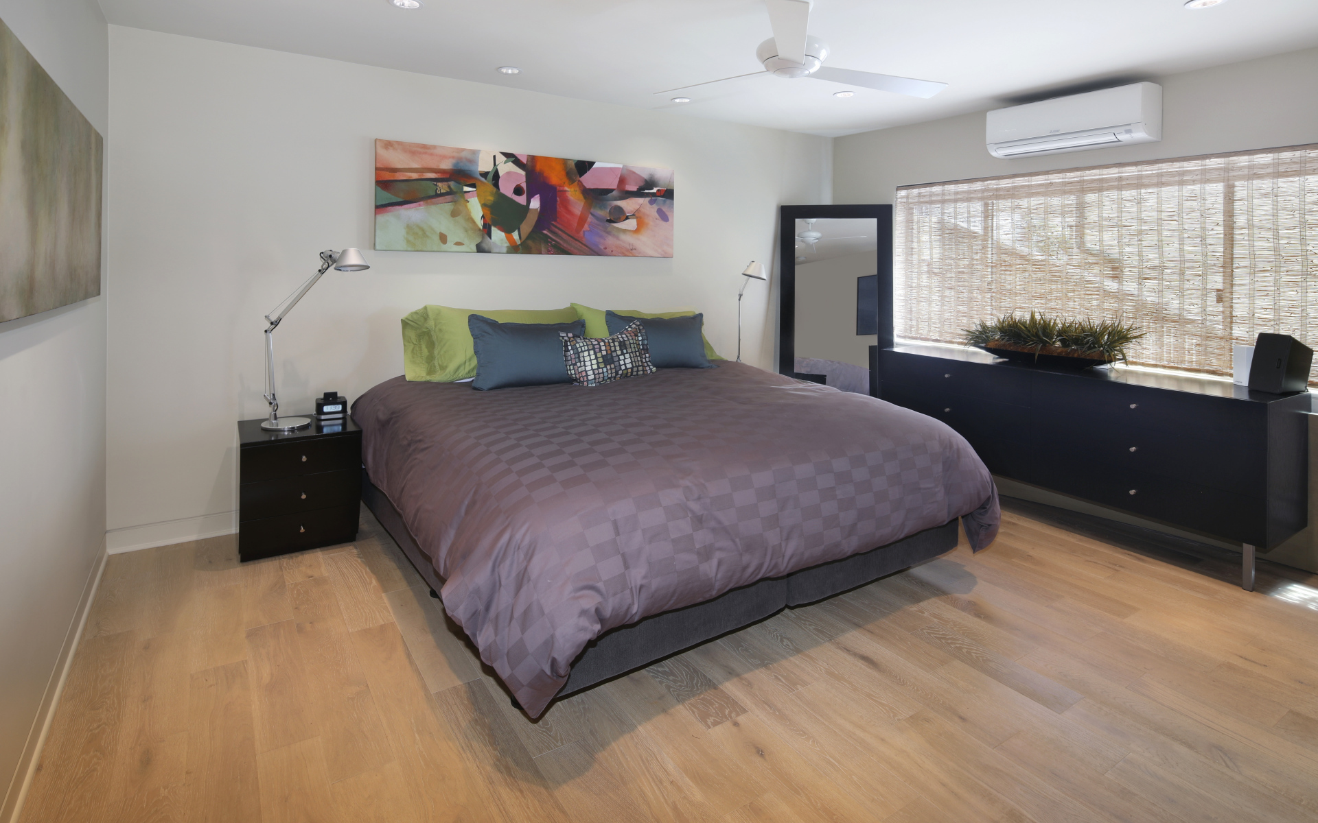 Большая серая кровать в спальне с белыми стенами