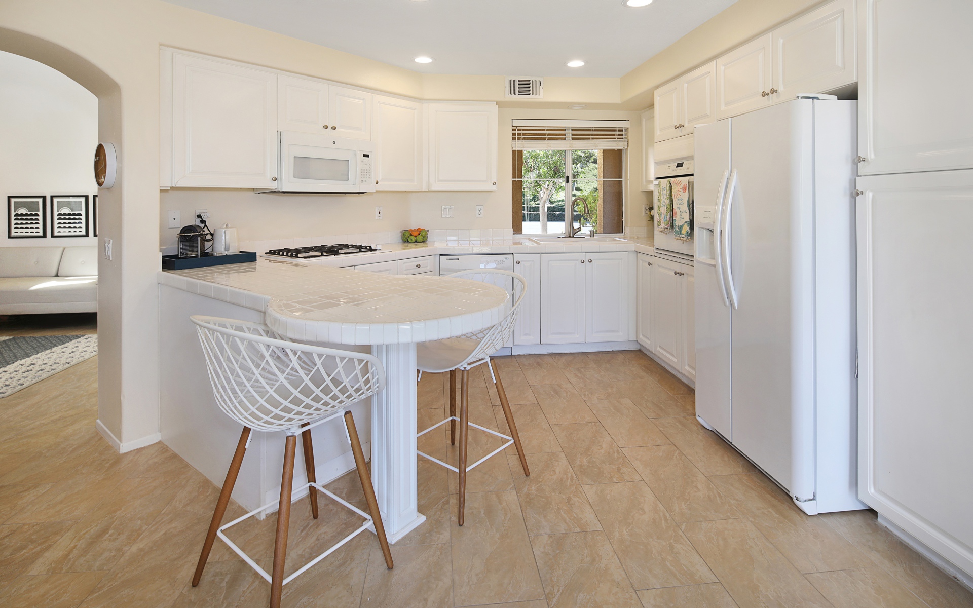 Белая стильная мебель с большим холодильником на кухне