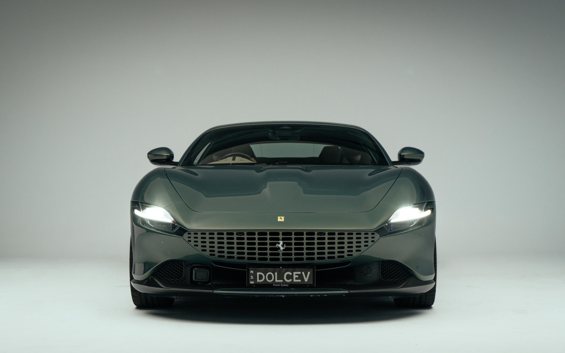 Автомобиль Ferrari Roma на сером фоне вид спереди