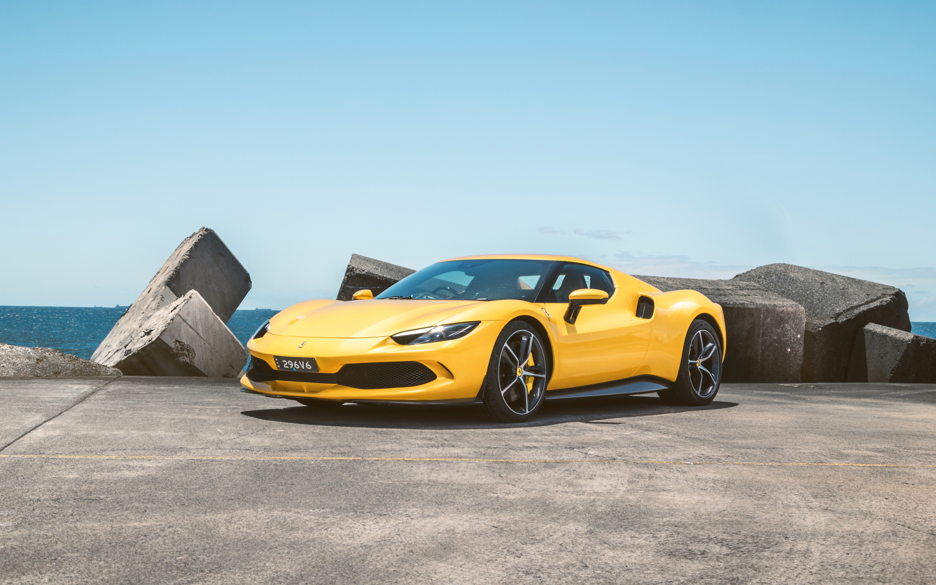 Желтый автомобиль Ferrari 296 GTB у камней