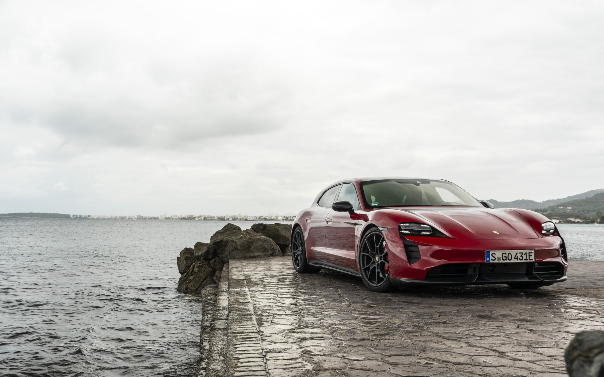 Красный автомобиль Porsche Taycan  у воды